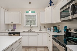 A kitchen with white cabinetry, a stainless steel microwave, and a coffee maker. - GaGa's Getaway: Quiet location, dog-Friendly, fire pit, 3-night min. (Kill Devil Hills)