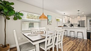 Une cuisine moderne avec des meubles blancs, une table à manger en bois et des tabourets de bar.
