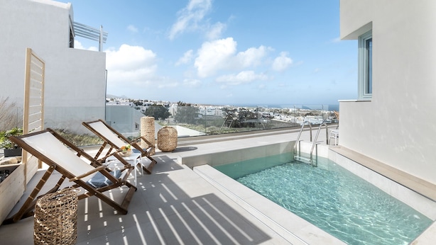 A rooftop pool area with lounge chairs and a view of the city. - Santo Bloom Luxury Villas with Sea View & Two Pools (Santorini)