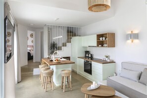 A modern kitchen with white cabinets, a wooden countertop, and a dining area with wicker stools.