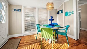 Una zona de menjador amb una taula i cadires, una làmpada penjant i decoracions a la paret.