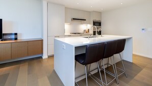 Una cucina moderna con isola centrale, sgabelli da bar ed elettrodomestici integrati.