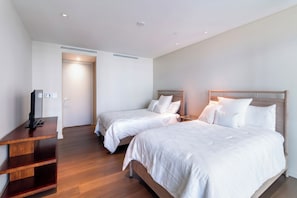 A hotel room with two beds, a TV stand, and a door leading to another room. - Special Offer for 2026! Luxury Condo "Park Lane" Unit #1505! (Honolulu)