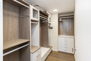 A walk-in closet with wooden shelving, a white dresser, and a hanging rod.
