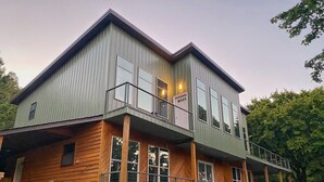 Una casa de dos pisos con fachada de madera y un balcón en el nivel superior.