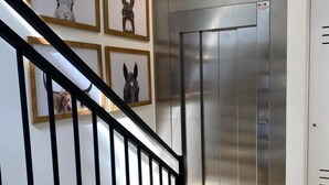 Eine Treppe mit schwarzer Geländer, die zu einem Aufzug führt.