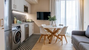 Eine kompakte Küche mit Waschmaschine, Mikrowelle und einer Essecke mit Tisch und Stühlen.