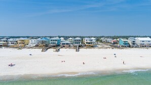 Une propriété située en bord de mer, comprenant plusieurs maisons, une jetée en bois et une plage de sable.