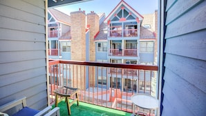 Ein Balkon mit Blick auf ein mehrstöckiges Gebäude mit Balkonen, einem kleinen Tisch und einem Stuhl.