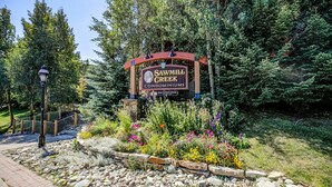 A sign for Sawmill Creek Condominiums surrounded by a landscaped garden with various plants and a stone pathway.