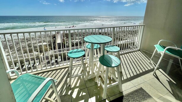A balcony with a view of the beach, featuring a railing, a table, and a chair. - 407 Island Princess~3BR 3Ba Gulf front with Balcony~FREE Beach Service (Fort Walton Beach)