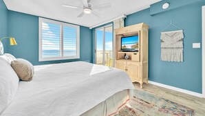 A bedroom with a bed, a ceiling fan, a TV, and a view of the beach through the window. - 407 Island Princess~3BR 3Ba Gulf front with Balcony~FREE Beach Service (Fort Walton Beach)