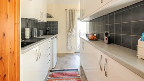 Una cocina moderna con armarios blancos, baldosas negras y una alfombra a rayas.