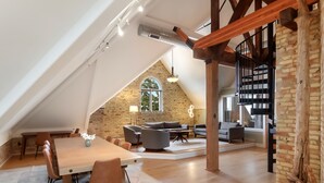 Un loft spacieux avec de hauts plafonds, des murs en briques apparentes et un escalier en bois.