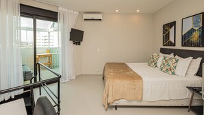 A hotel room with a bed, a TV mounted on the wall, and a balcony with a glass door. - OFP - Duplex na Oscar Freire By Anora Spaces (São Paulo)