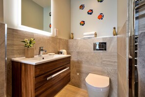 Un baño moderno con tocador de madera, inodoro y decoración de peces en la pared.