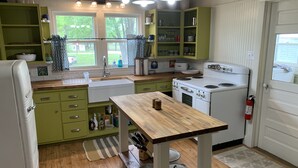 A kitchen with green cabinets, a white stove, and a wooden table. - Step Back in Time Near The Missouri River (Jamestown)