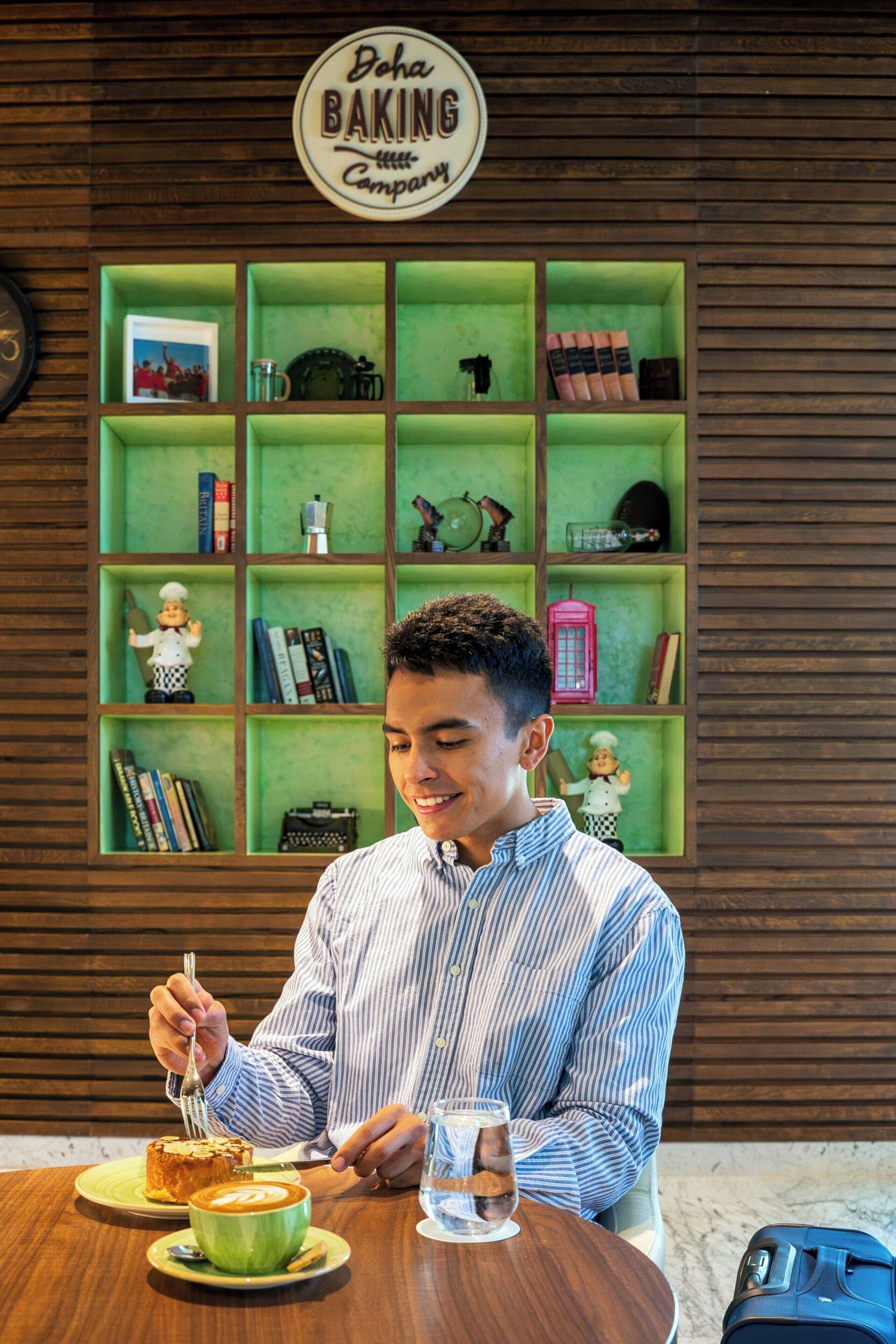 A person dining at a table with a cake and a cup of coffee.