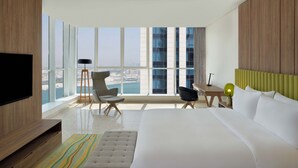 A modern hotel room with a large bed, a television, a desk, and a chair. The room has large windows offering a view of the city. - Element by Marriott City Center Doha (Doha)