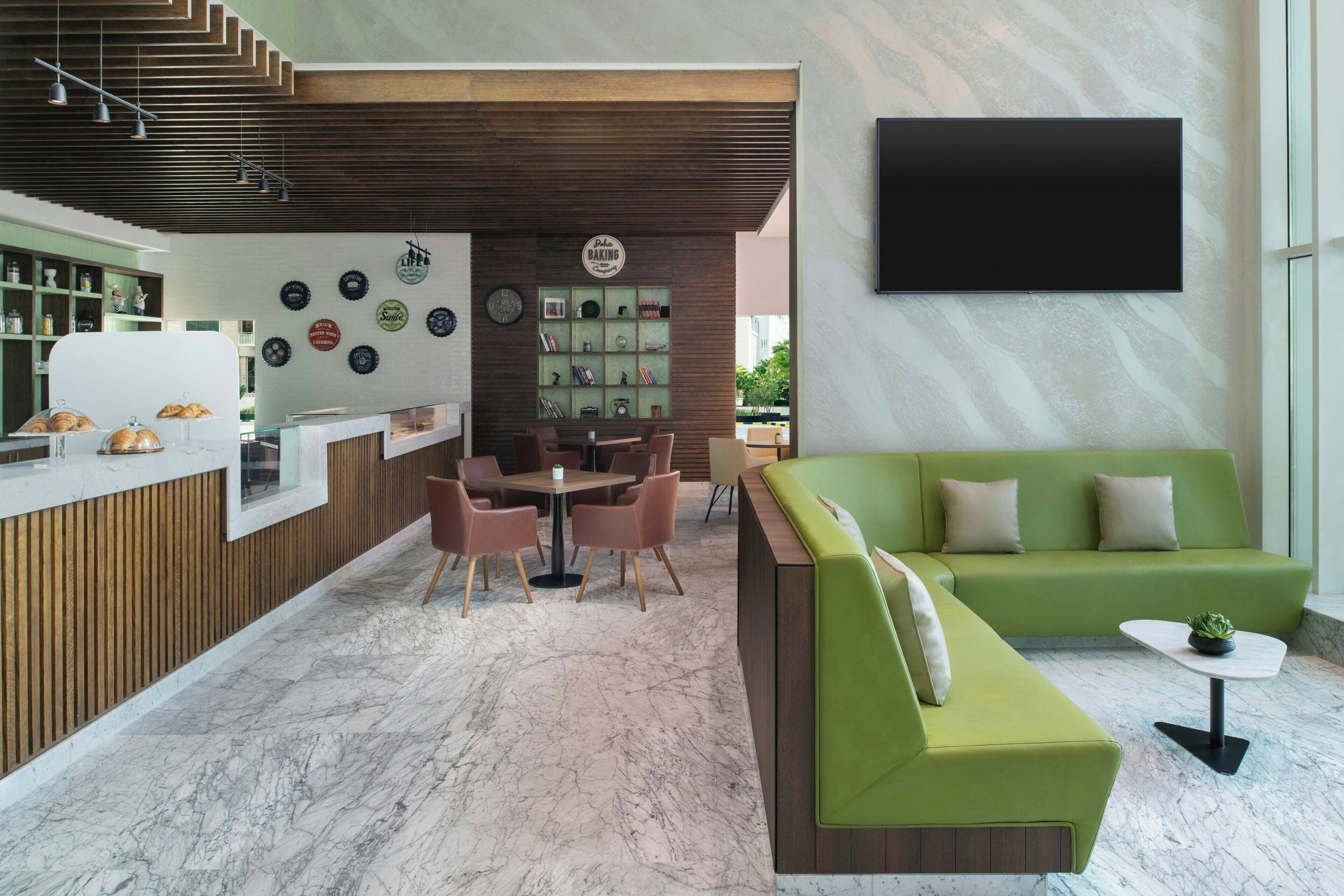A modern interior with a reception desk, seating area, and a flat-screen TV mounted on the wall.