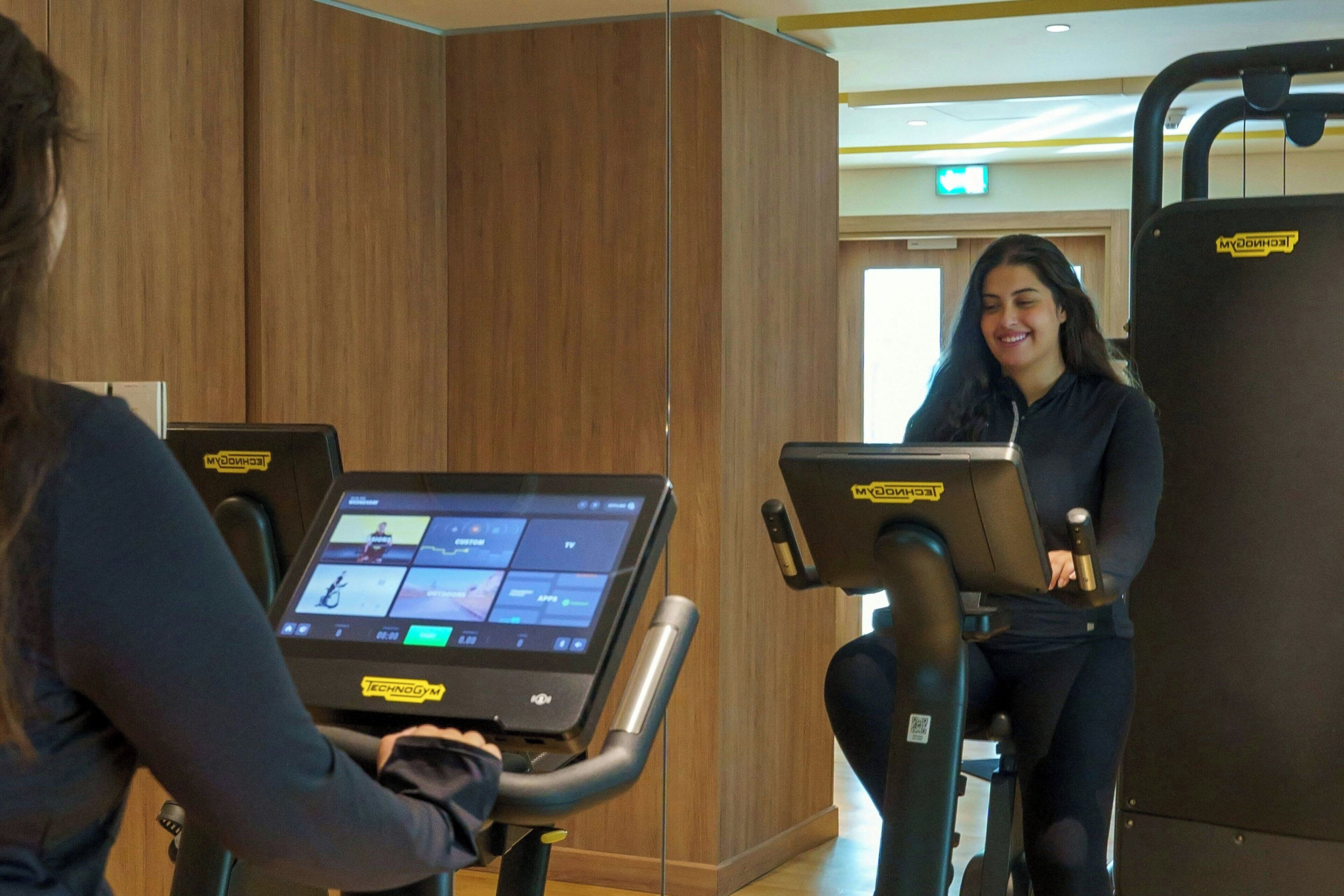 Un gimnasio con equipo de ejercicio e interfaz digital.