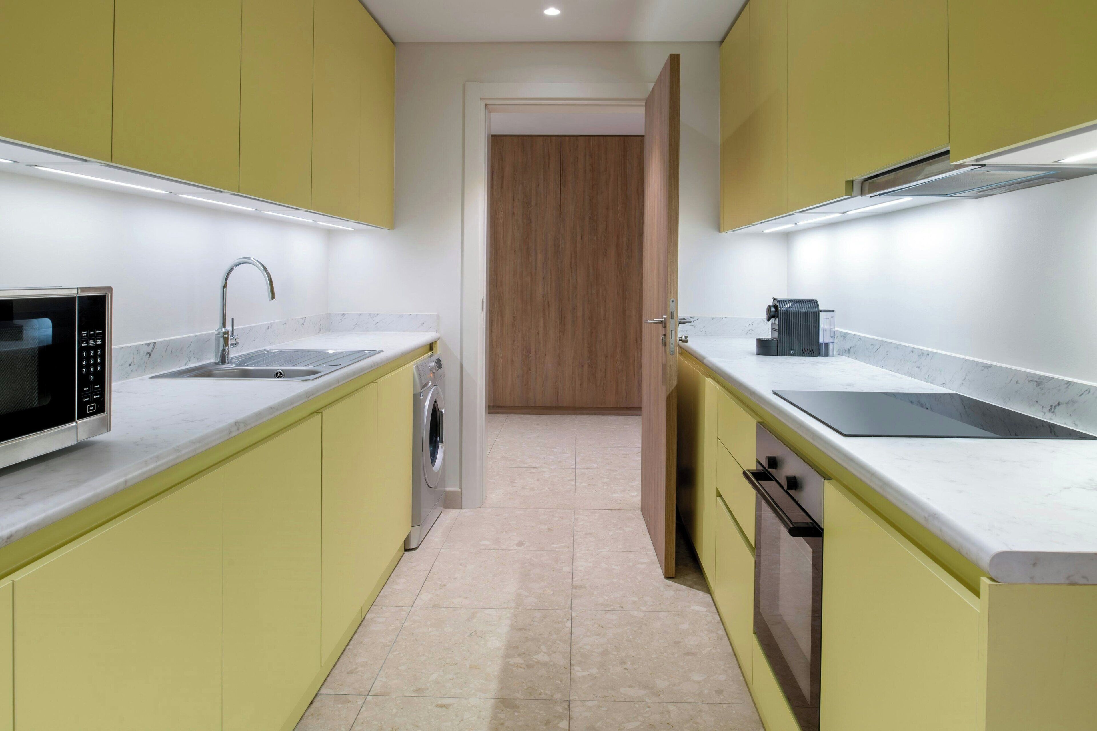 Cocina compacta con armarios amarillos, microondas integrado, fregadero y estufa.