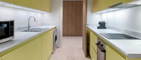Cocina compacta con armarios amarillos, microondas integrado, fregadero y estufa.