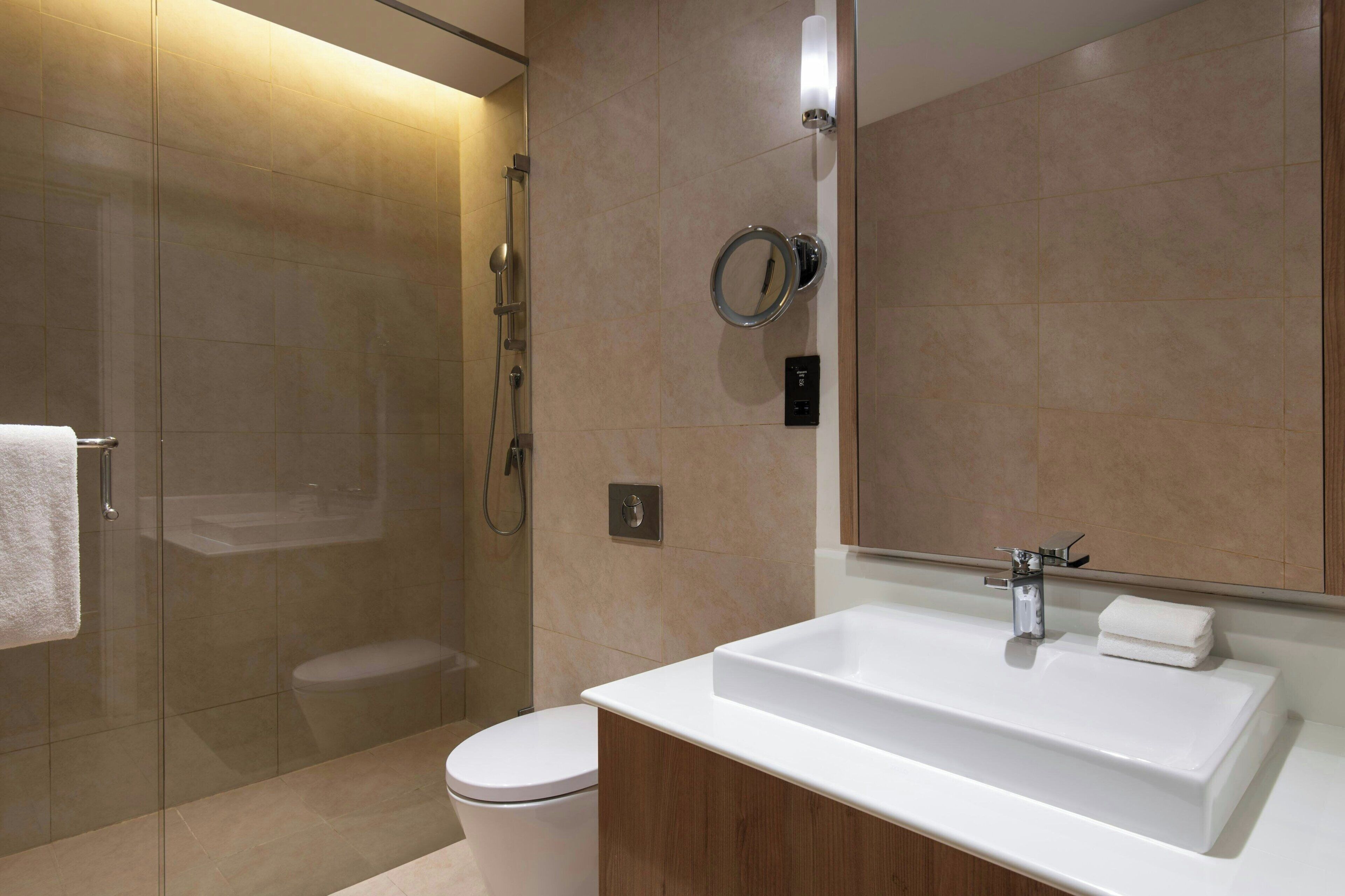 A modern bathroom with a glass-enclosed shower, a white sink, and a mirror.