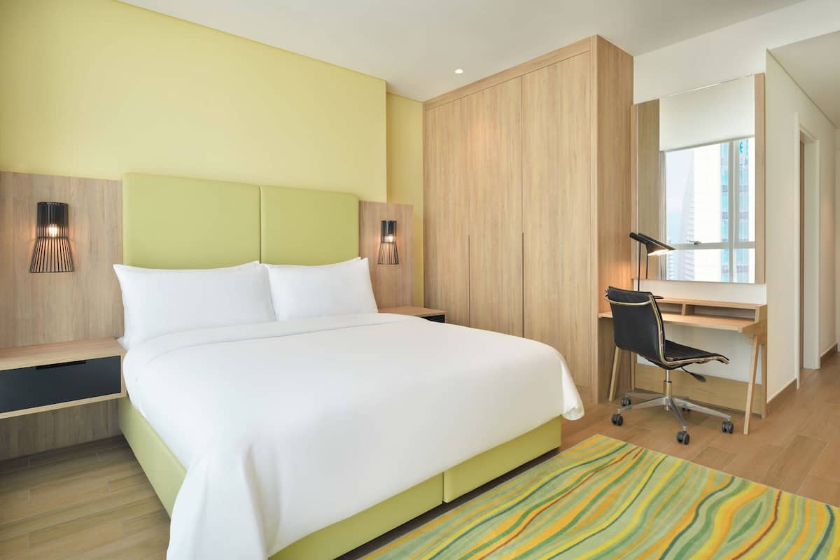Una habitación de hotel moderna con una cama grande, un escritorio y una silla.