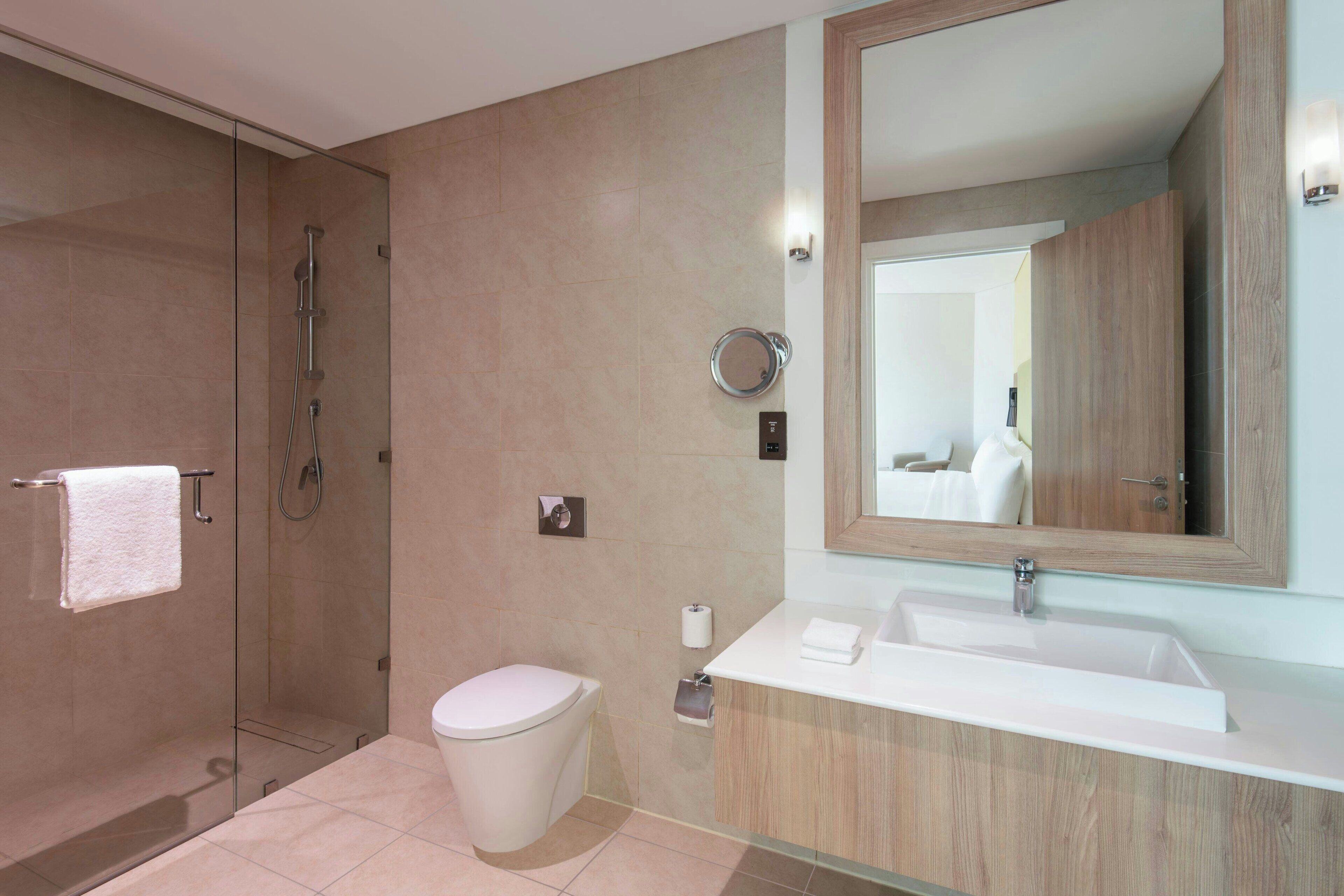 A modern bathroom with a glass shower enclosure, a toilet, a sink with a mirror, and a towel rack.