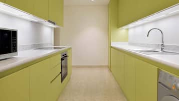 A compact kitchen with green cabinets, a microwave, an oven, a dishwasher, and a washing machine.