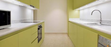 Cocina compacta con gabinetes verdes, microondas, horno, lavavajillas y lavadora.