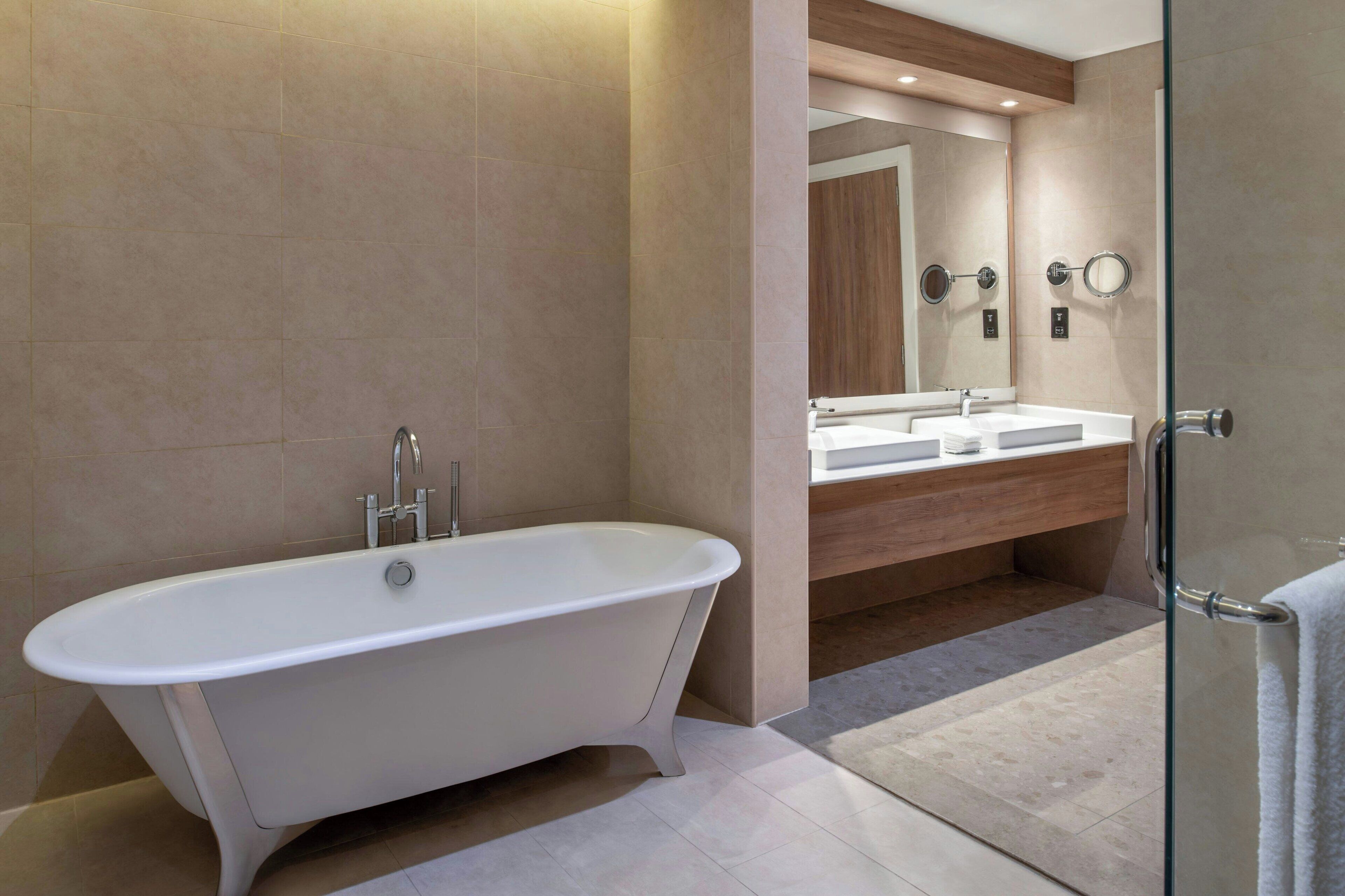 A modern bathroom with a freestanding bathtub, a vanity with a mirror, and a glass shower enclosure.