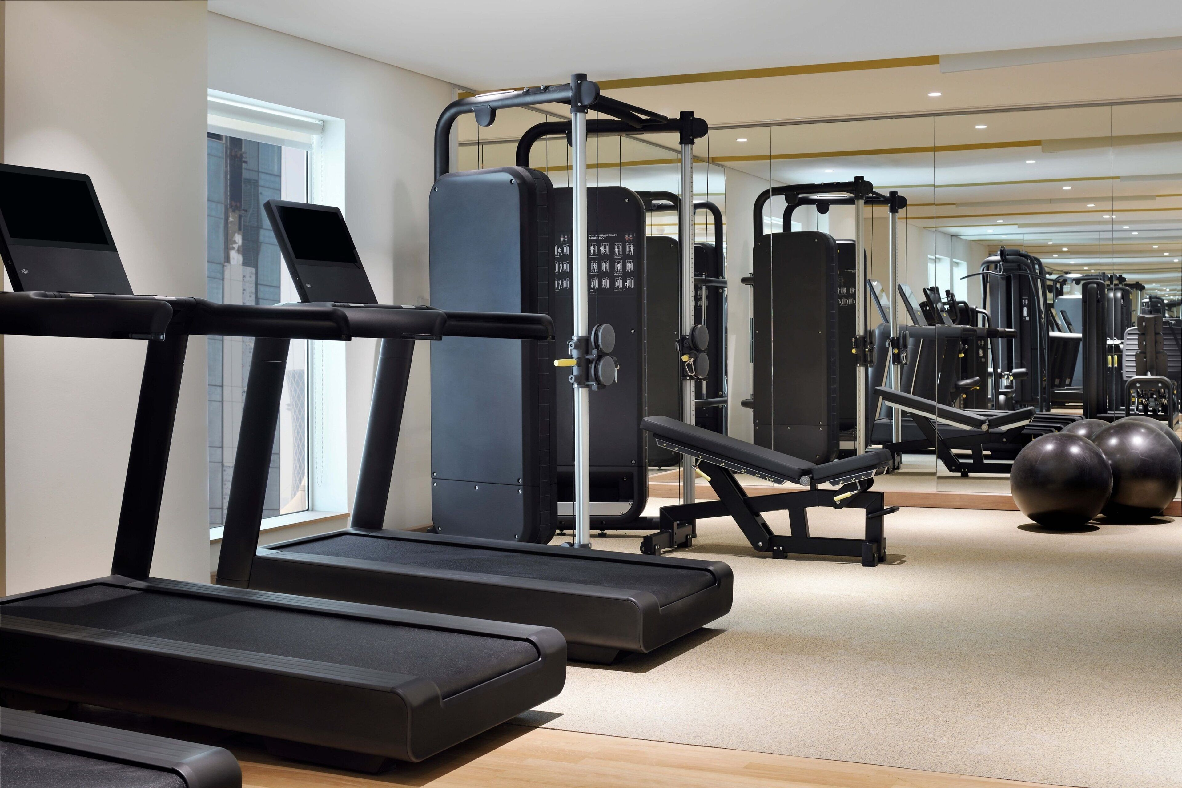 Ein Fitnessstudio mit Laufbändern, Kraftgeräten und Übungsbällen.