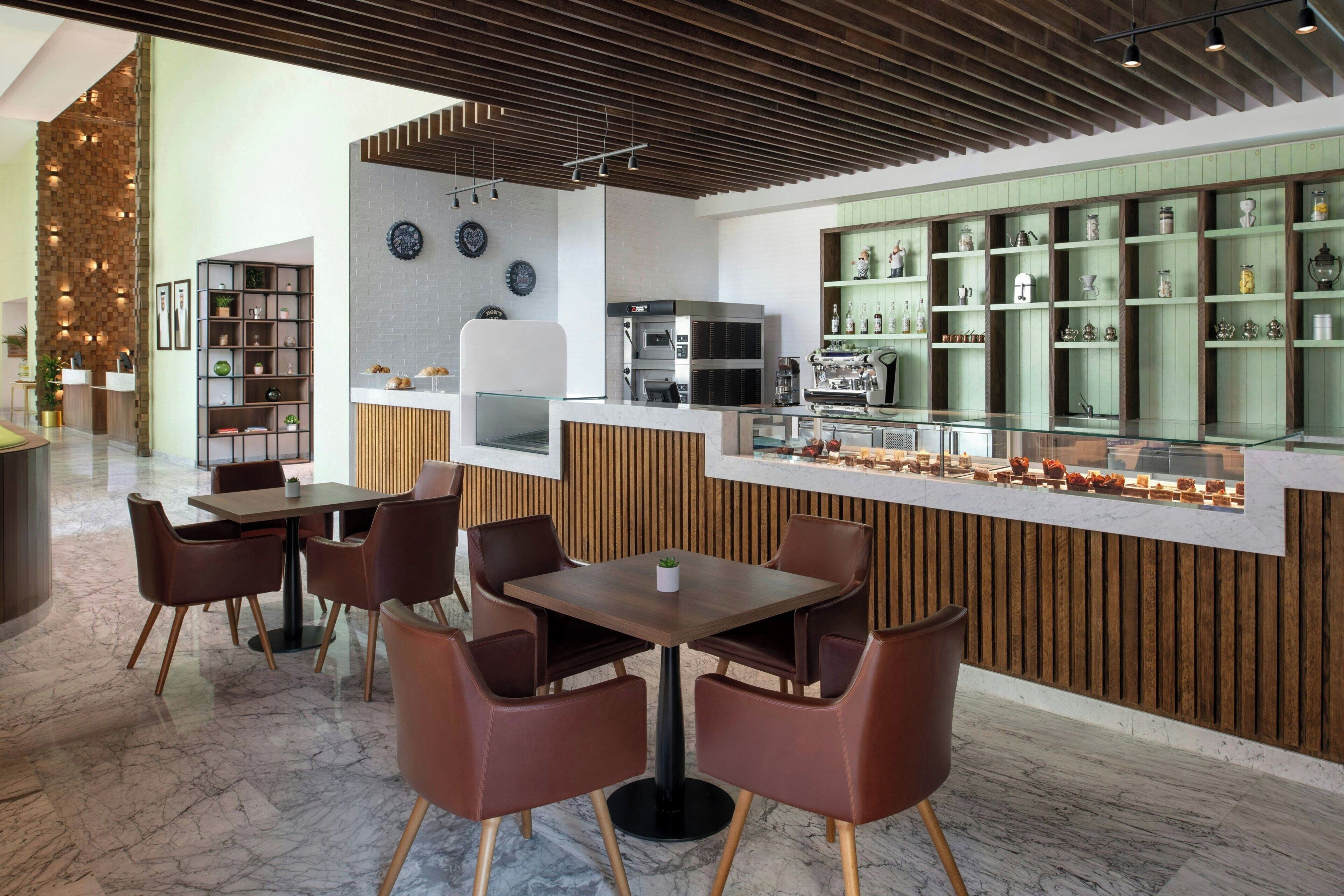 A modern restaurant with a wooden ceiling, marble flooring, and a counter with glass display cases.