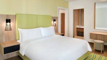 A hotel room with a large bed, bedside tables, a mirror, and a bathroom visible through an open door.