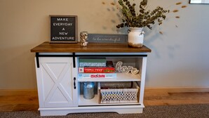 Une console en bois sur laquelle est posée une pancarte portant l’inscription « FAITES DE CHAQUE JOUR UNE NOUVELLE AVENTURE » et un vase rempli de fleurs séchées.