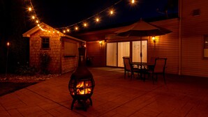 Une terrasse dotée d’un poêle à bois, de mobilier d’extérieur et de guirlandes lumineuses.
