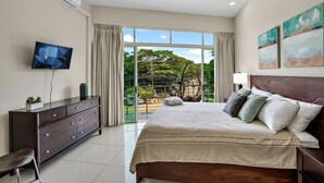 A bedroom with a bed, a TV, a dresser, and a view of the outdoors. - PP201: Modern Space in Centre of Town (Tamarindo)