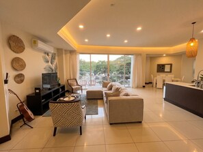 A modern living room with a sofa, ottoman, and a dining area with a table and chairs. - PP201: Modern Space in Centre of Town (Tamarindo)
