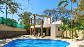 A swimming pool with lounge chairs, a covered outdoor area, and palm trees. - PP201: Modern Space in Centre of Town (Tamarindo)