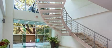 Un interior espacioso con una escalera de caracol, ventanas amplias y plantas en macetas.