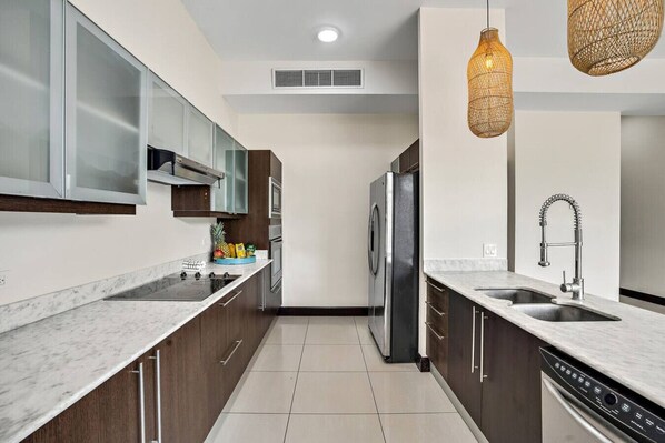 A modern kitchen with a stainless steel refrigerator, double sink, and wooden cabinets.