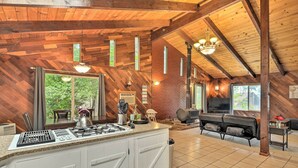 A spacious kitchen with a large island, wooden ceiling beams, and a dining area with a sofa and grill. - Step-Free Hawkins Bar Home Near Trinity River (Salyer)