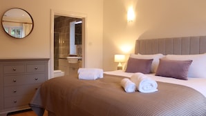 A hotel room with a bed, a dresser, a bathroom, and a mirror. - The Anchorage @ Nables Farm (Chippenham)