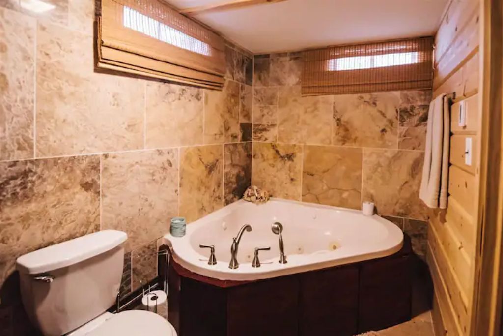 A bathroom with a marble wall, a bathtub, and a toilet.