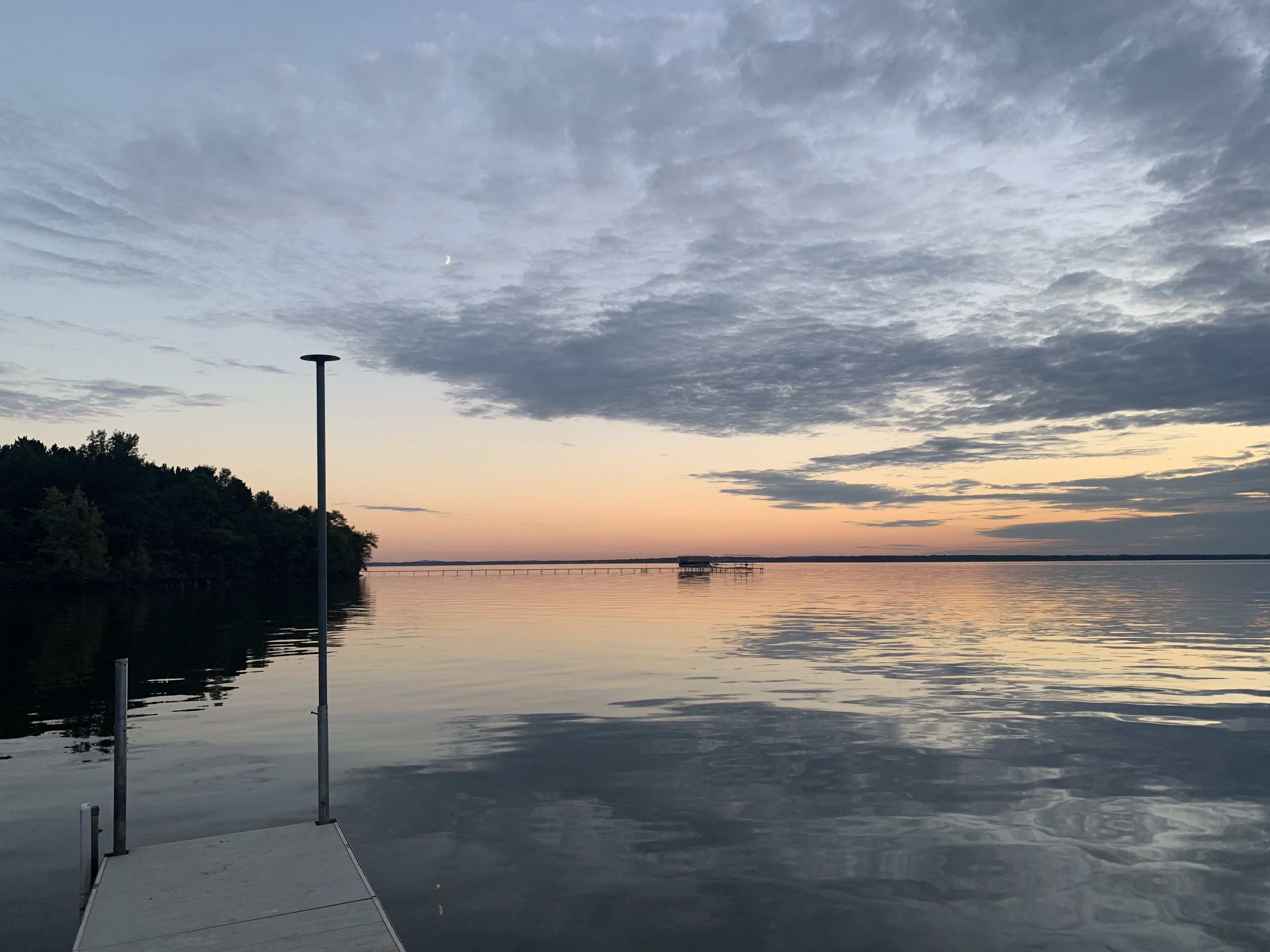 Een rustig meer bij zonsondergang, met een steiger en pier die in het water uitsteken.
