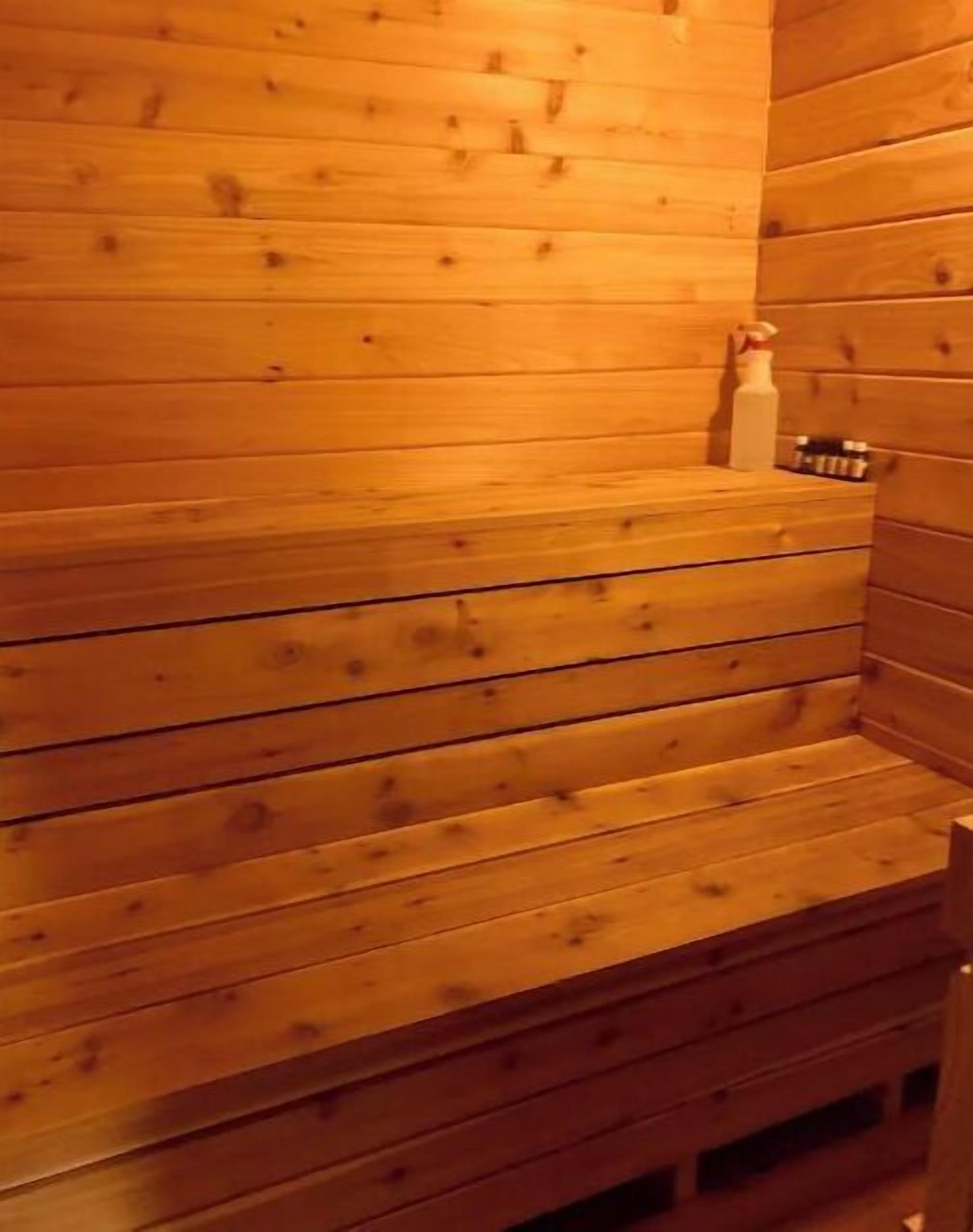 A wooden sauna with benches and a shelf holding bottles.