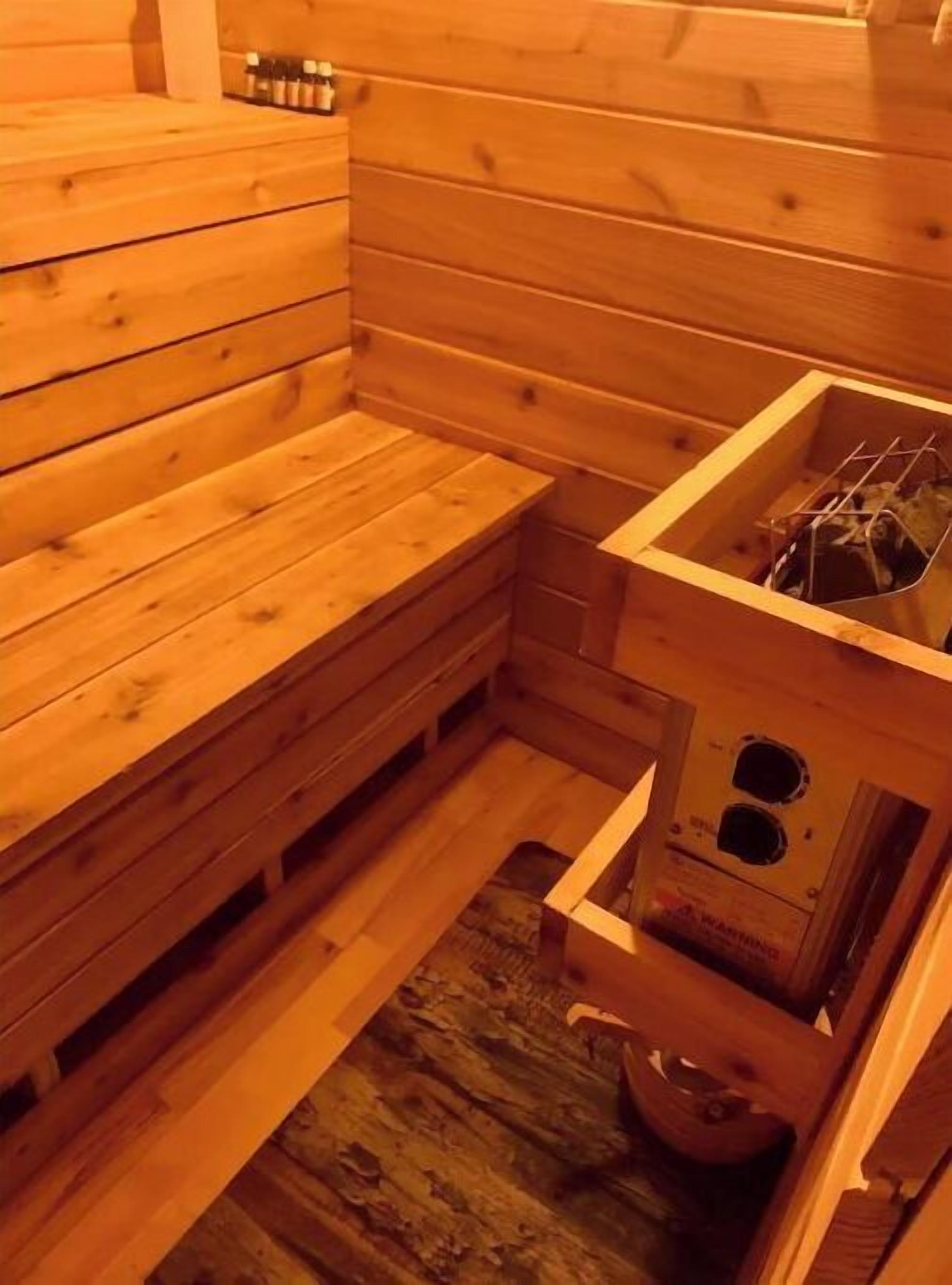 Un sauna en bois avec des bancs et un petit coin lavabo.
