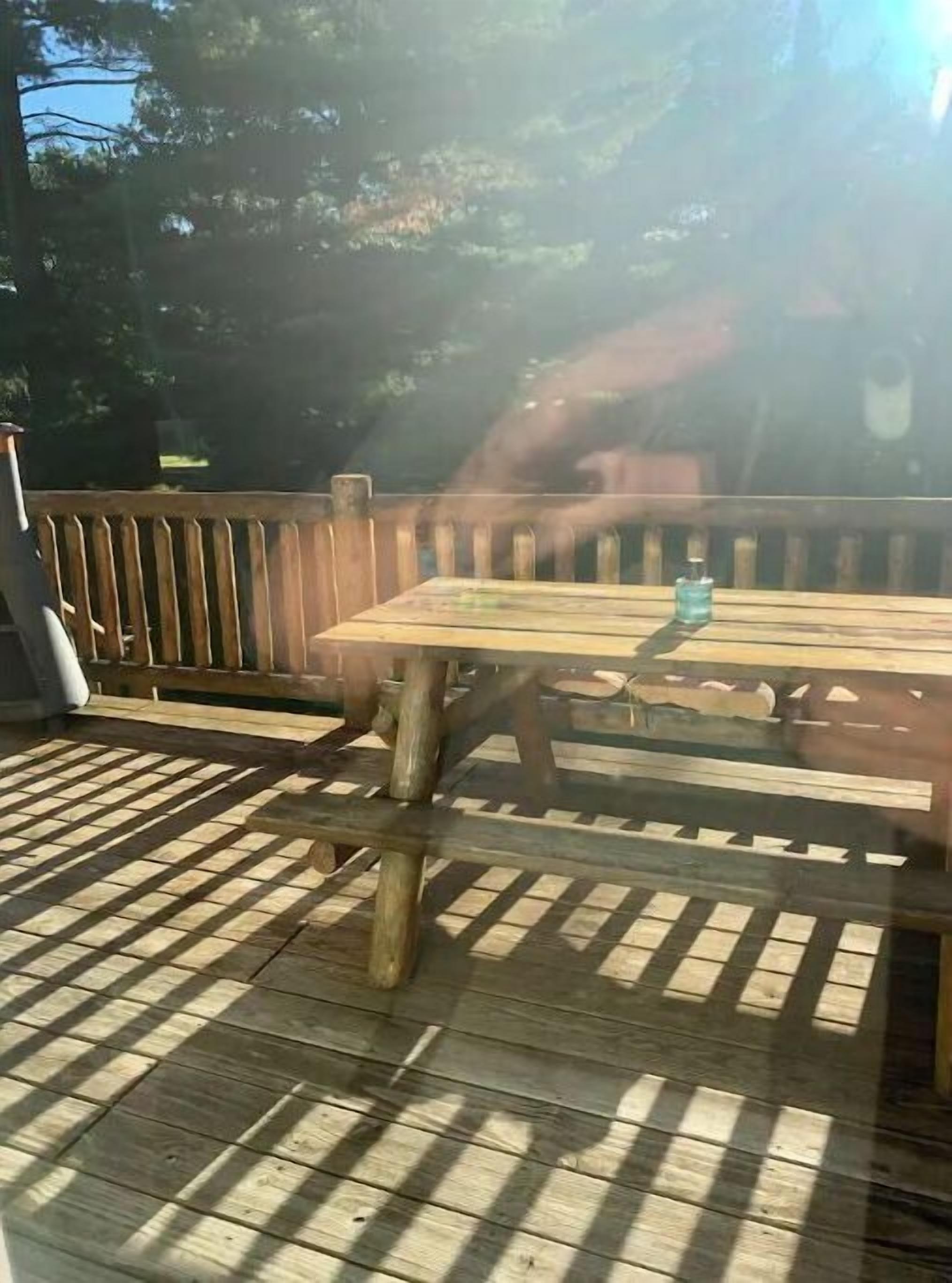 Una terraza de madera con una mesa y sillas, rodeada por un cerco de madera.